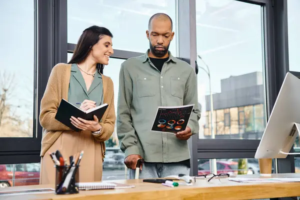 A man and a woman, both professionally dressed, brainstorming in front of a computer in a modern office space. — Stock Photo