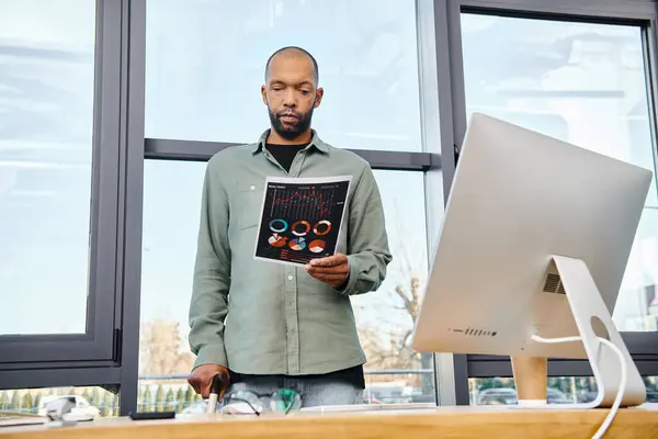 Un homme dans un bureau debout devant un grand écran d'ordinateur, immergé dans le travail sur un projet pour son entreprise. — Photo de stock
