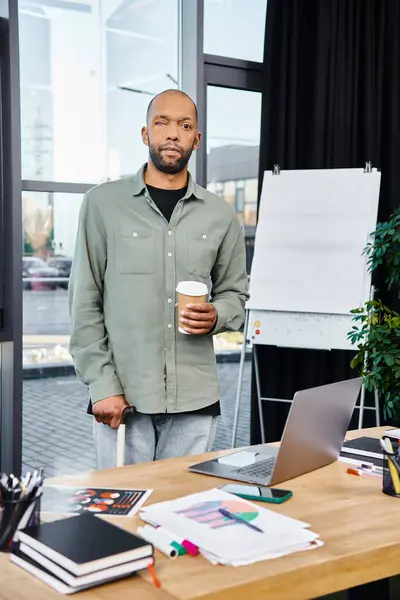 Ein Mann steht selbstbewusst vor einem Schreibtisch, fokussiert auf seinen Laptop-Bildschirm und verkörpert das Wesen der Unternehmenskultur und Produktivität. — Stockfoto