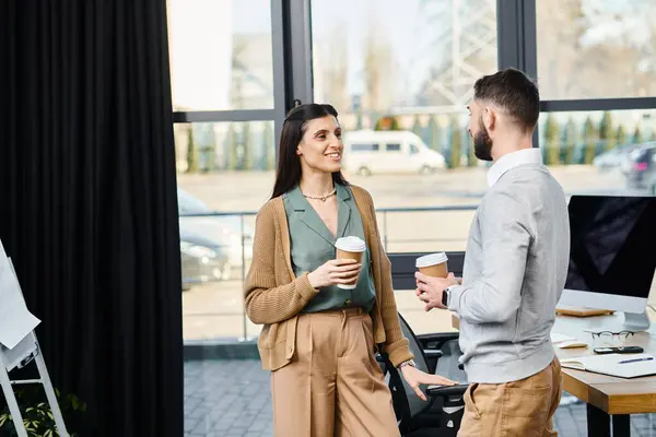 Un hombre y una mujer entablan un diálogo estratégico dentro de un entorno de oficina corporativa, profundamente en la conversación. - foto de stock