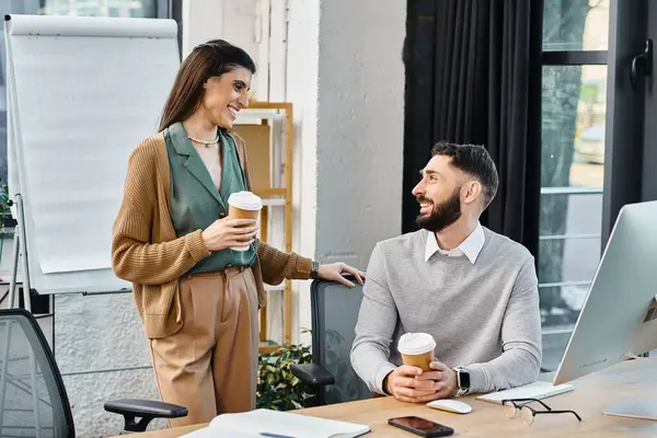Un hombre y una mujer participan en una discusión en un entorno de oficina corporativa, rodeado de documentos y tecnología relacionados con el trabajo. - foto de stock