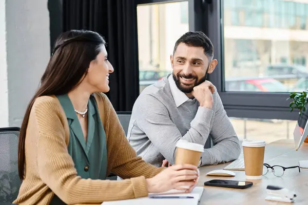 Un homme et une femme engagés dans une conversation réfléchie à une table, immergés dans une discussion approfondie dans un cadre de bureau. — Photo de stock