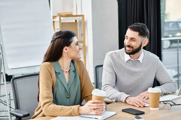 A man and a woman engaged in a conversation at a table, discussing a project in a corporate office setting. — Stock Photo