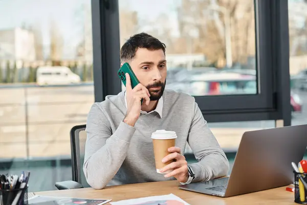Un hombre en un entorno de negocios, sentado en una mesa, participando en una conversación telefónica. - foto de stock