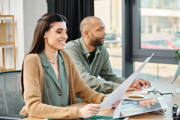 A man and a woman are working together on a project at a table with a laptop in a corporate office setting. — Stock Photo