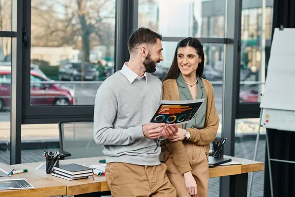 Un homme et une femme en tenue de travail debout côte à côte, symbolisant le travail d'équipe et la collaboration dans un cadre de bureau moderne. — Photo de stock