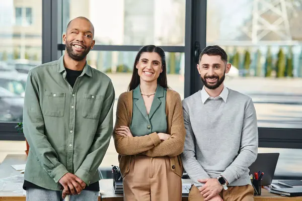 Three individuals, engaged in discussion, stand together in an office setting, embodying corporate collaboration and innovation. — Stock Photo