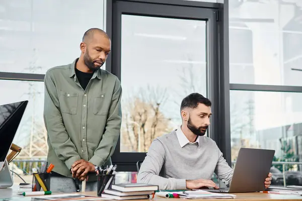 Two men engrossed in laptop, brainstorming ideas, working on a project in a modern office setting. — Stock Photo