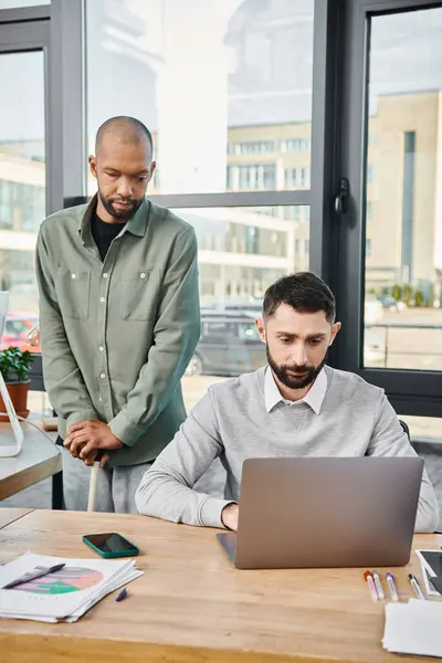 Два бизнесмена в офисе, работающие с ноутбуком, их лица вдумчивы и сосредоточены, в разгар продуктивной рабочей сессии. — стоковое фото