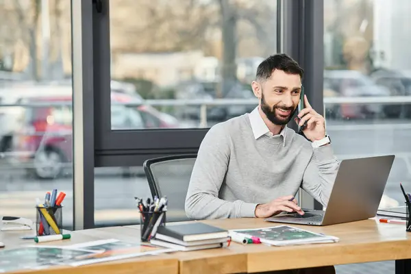 A man in a business setting talking on a cell phone at a desk. — Stock Photo