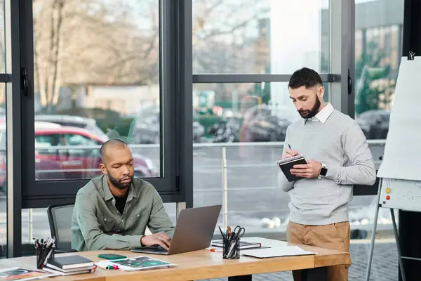 Two men deeply engrossed in their laptops, engaged in a collaborative coding session at a modern office table, diversity and inclusion — Stock Photo