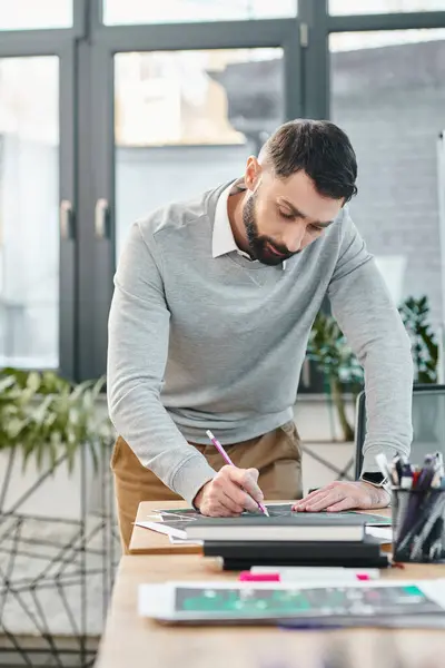 Un uomo alla scrivania, concentrato e scritto su un pezzo di carta, immerso nel progetto di business a cui sta lavorando. — Foto stock