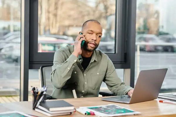 Homme noir assis à un bureau, pleinement engagé sur un appel téléphonique cellulaire, profondément dans la conversation. — Photo de stock