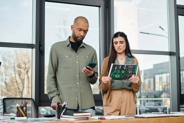 A man with myasthenia gravis and a woman stand in an office, engaged in discussion while looking at charts, showcasing teamwork in a corporate setting. — Stock Photo