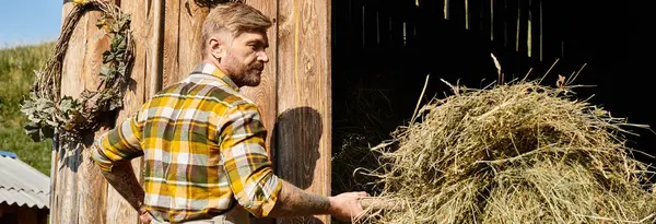 Bom agricultor olhando em traje casual usando forquilha enquanto trabalhava com feno na aldeia, banner — Fotografia de Stock