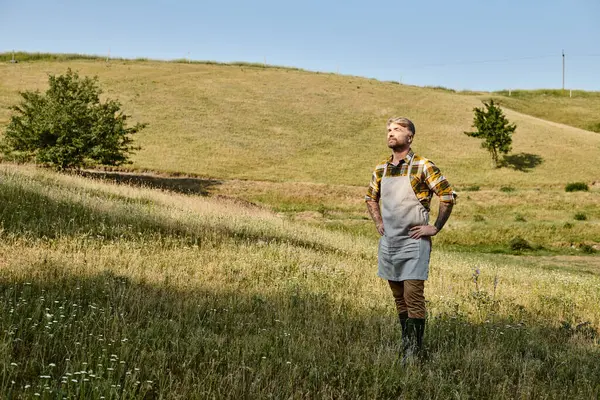 Attraktiver moderner Bauer mit Tätowierungen und Bart entspannt auf seinem Hof und schaut weg — Stockfoto
