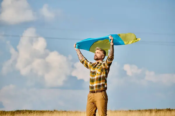 Atraente ucraniano homem em traje casual posando com bandeira nacional, paisagem cênica, agricultor moderno — Fotografia de Stock