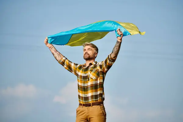 Atractivo hombre ucraniano en traje casual posando con bandera nacional, paisaje escénico, agricultor moderno - foto de stock