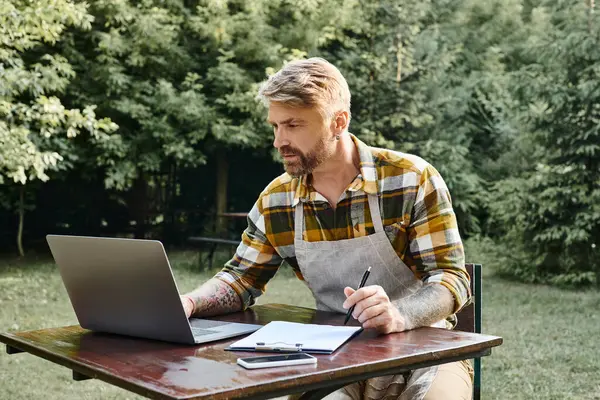 Жорсткий робочий красивий чоловік з бородою використовує ноутбук і буфер обміну для аналізу ресурсів на фермі — стокове фото