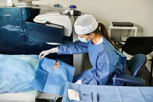 A surgeon in a gown operates a machine for laser vision correction. - foto de stock