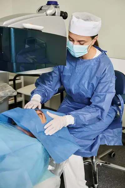 Una mujer con una bata de hospital opera una máquina para la corrección de la visión láser. - foto de stock