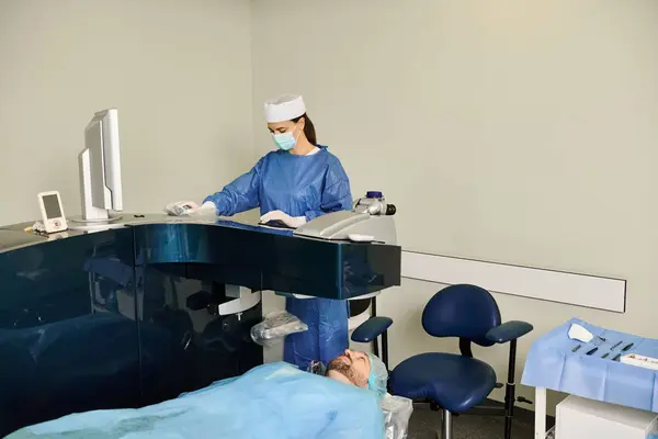 Médico em esfoliação realizando cirurgia usando um computador em um ambiente médico. — Fotografia de Stock