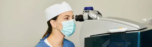 Mujer con máscara quirúrgica que sostiene la máquina de corrección de visión láser. - foto de stock