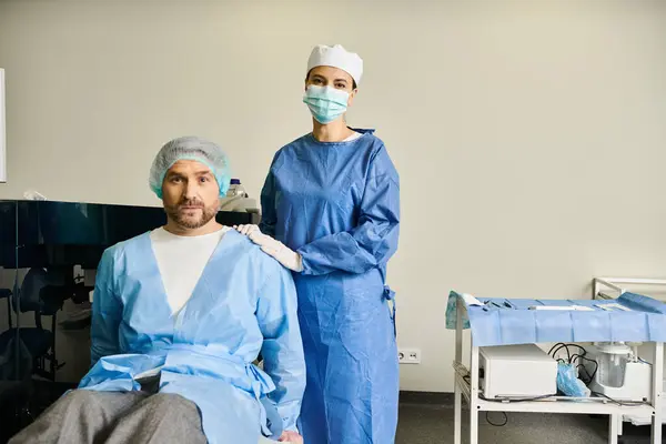 Женщина стоит в больничном платье рядом с мужчиной на больничной койке. — стоковое фото