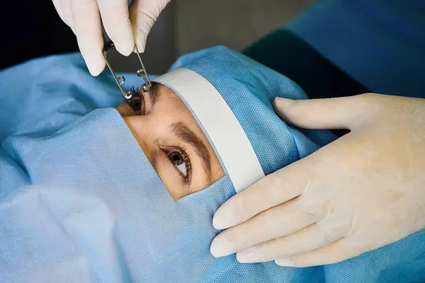 Doctor devoto realizando corrección de la visión láser en la cara de las mujeres. - foto de stock