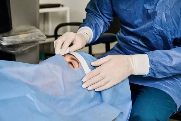 Una mujer con una camisa azul y guantes blancos que recibe corrección de visión láser en el consultorio médico. - foto de stock