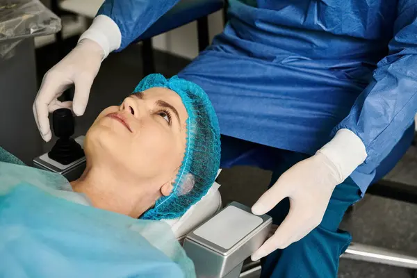 Uma pessoa com esfoliação azul e luvas brancas realiza correção da visão a laser em um consultório médico. — Fotografia de Stock