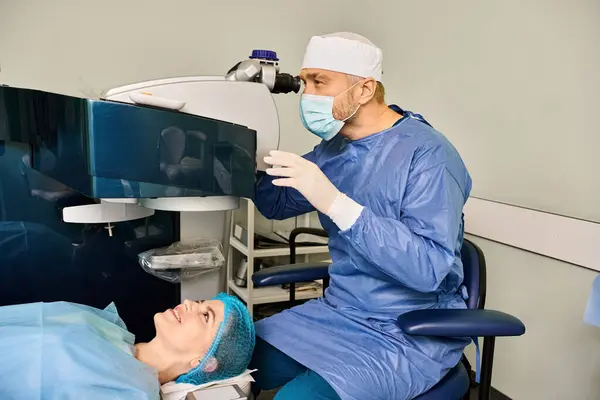 Un uomo in un abito blu scrub e una donna in un abito blu a una sessione di correzione della visione laser. — Foto stock