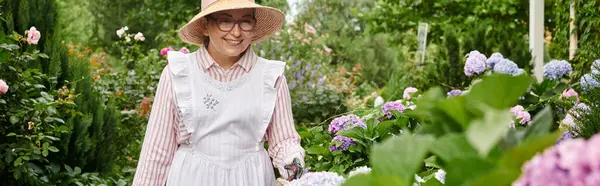 Jolly donna matura con grembiule e attrezzi da giardinaggio prendersi cura di bella ortensia, banner — Foto stock