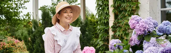 Belle femme joyeuse mature en robe et tablier prenant soin actif de son hortensia vibrante, bannière — Photo de stock