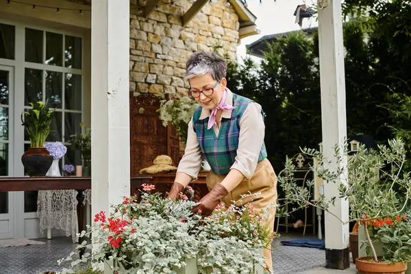 Good looking chic mature woman with glasses taking care of her flowers near her house in England — Stock Photo