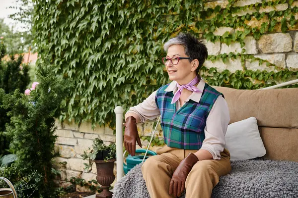 Boa aparência alegre mulher madura sentada no sofá perto de sua casa na Inglaterra e olhando para longe — Fotografia de Stock