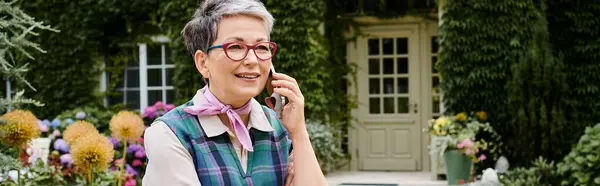 Elegante mujer madura alegre con gafas hablando por la red telefónica a su casa en Inglaterra, bandera - foto de stock