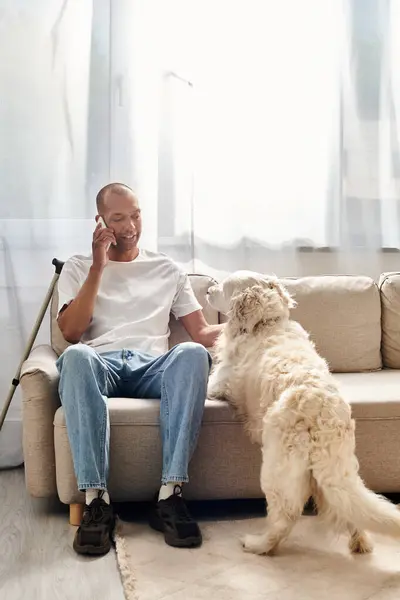 Um homem com miastenia gravis conversa no celular perto de seu cão Labrador em casa. — Fotografia de Stock