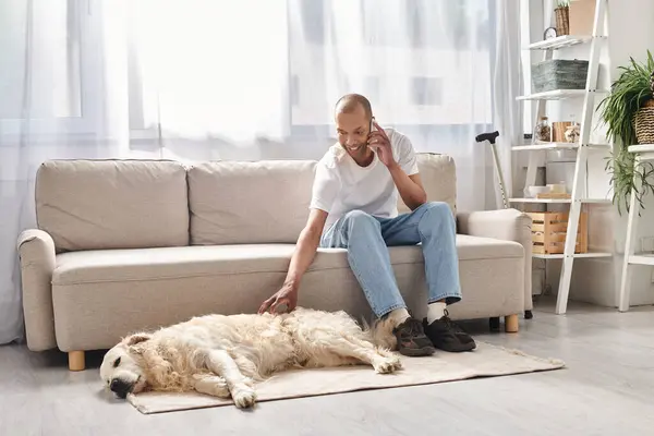 Un uomo afroamericano con miastenia gravis seduto su un divano accanto al suo fedele cane Labrador, che incarna diversità e inclusione. — Stock Photo