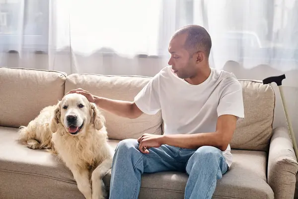 Un homme handicapé atteint de myasthénie grave s'assoit sur un canapé pour caresser un chien du Labrador, mettant en valeur la diversité et l'inclusion. — Photo de stock