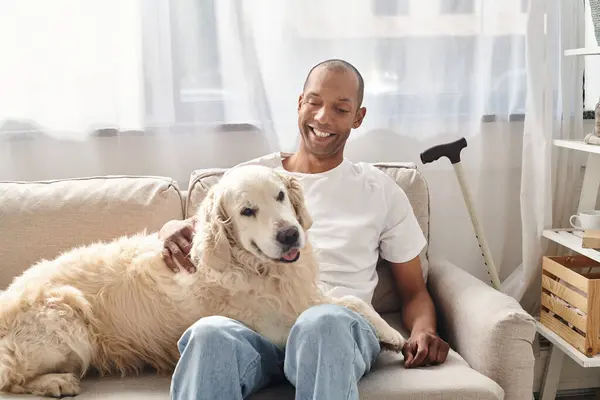 Um homem afro-americano deficiente com miastenia gravis e seu cão Labrador encontrando consolo em um sofá em casa. — Fotografia de Stock