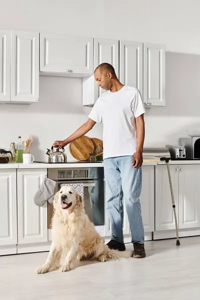 An African American man with myasthenia gravis standing in a kitchen with his Labrador dog, showcasing diversity and inclusion. — Stock Photo