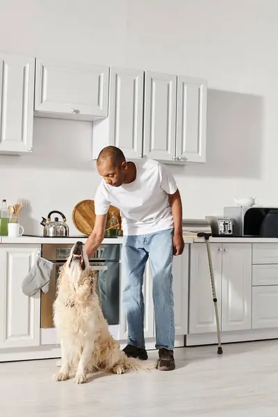 An African American man with myasthenia gravis stands in a kitchen, sharing a harmonious moment with his Labrador dog. — Stock Photo