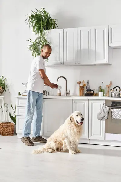 Un Afro-Américain atteint de myasthénie se tient à côté de son chien du Labrador dans une cuisine confortable, partageant un moment de connexion. — Photo de stock