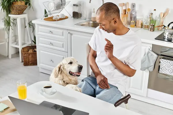 Ein Afroamerikaner mit Behinderung und sein Labrador Retriever genießen einen gemeinsamen Moment in einer gemütlichen Küche. — Stockfoto