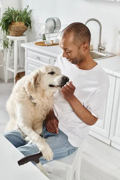 Un uomo afroamericano disabile accarezza amorevolmente il suo fedele Labrador in un accogliente ambiente cucina, irradiando calore e compagnia.. — Foto stock