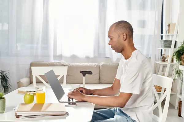 A disabled African American man with myasthenia gravis syndrome using a laptop computer at a table. — Stock Photo