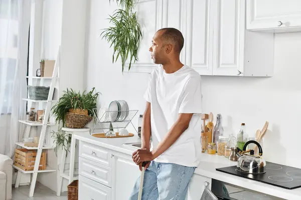 An African American man with myasthenia gravis syndrome standing in a kitchen, preparing a meal on a stove top oven. — Stock Photo