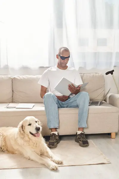 Инвалид афроамериканец с синдромом миастении, сидящий на диване рядом с собакой-лабрадором, олицетворяющий разнообразие и включение. — стоковое фото