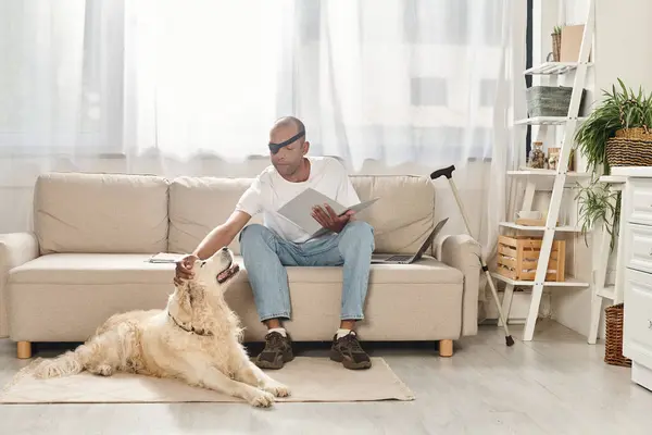A disabled African American man with myasthenia gravis syndrome sits on a couch next to his Labrador dog. — Stock Photo